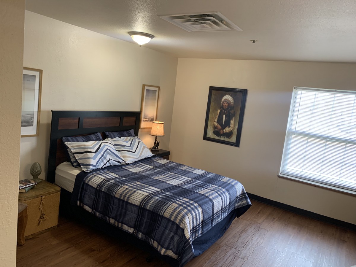 A neatly arranged bedroom with a bed, lamp, and window.