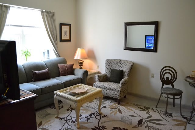 A cozy living room with a sofa, armchair, and coffee table complementing a soft lamp light.
