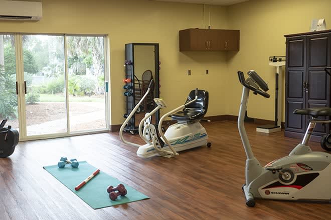 A home gym setup with exercise equipment including a stationary bike, a yoga mat, and dumbbells.