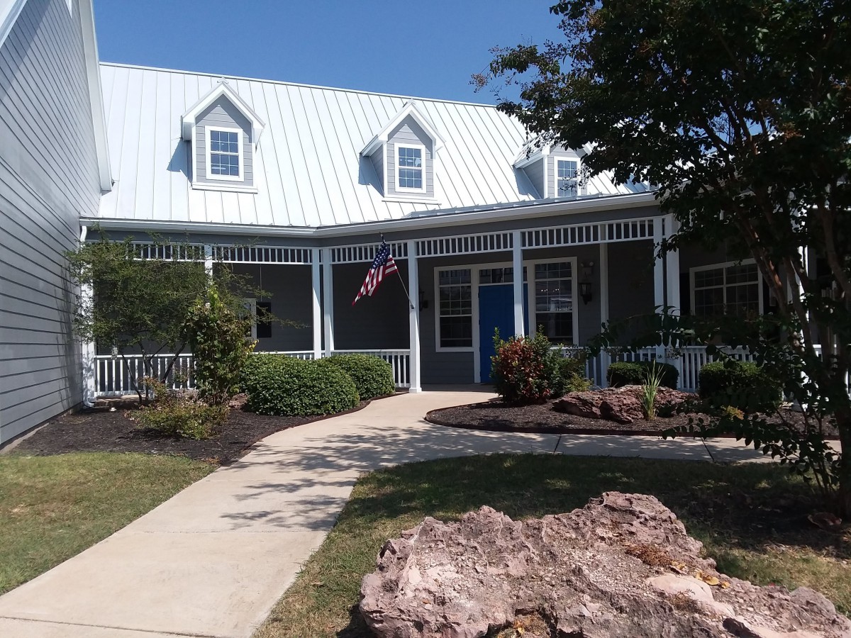 A charming house with a porch, surrounded by a garden and featuring an American flag.