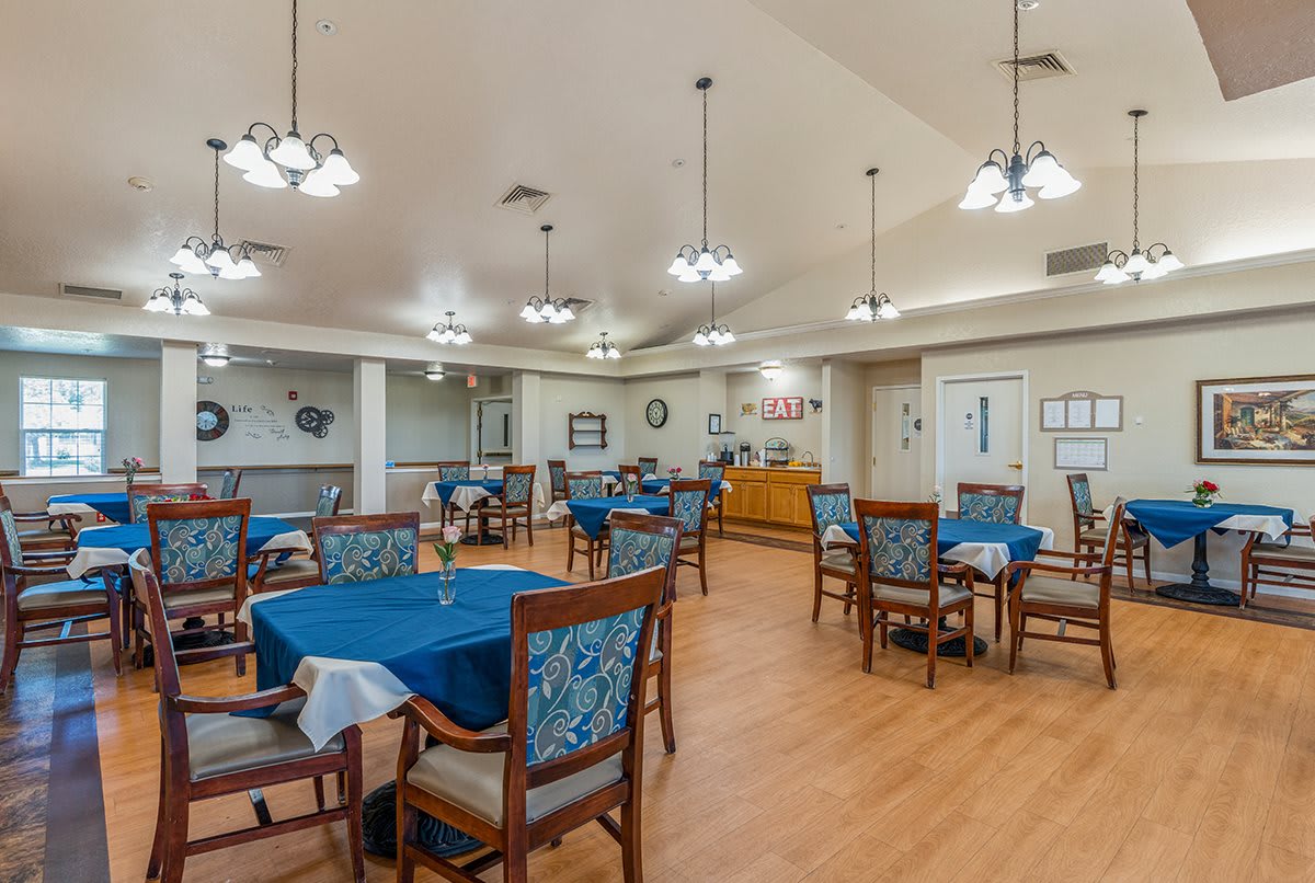 An empty dining room with several tables and chairs, featuring elegant lighting and decor.