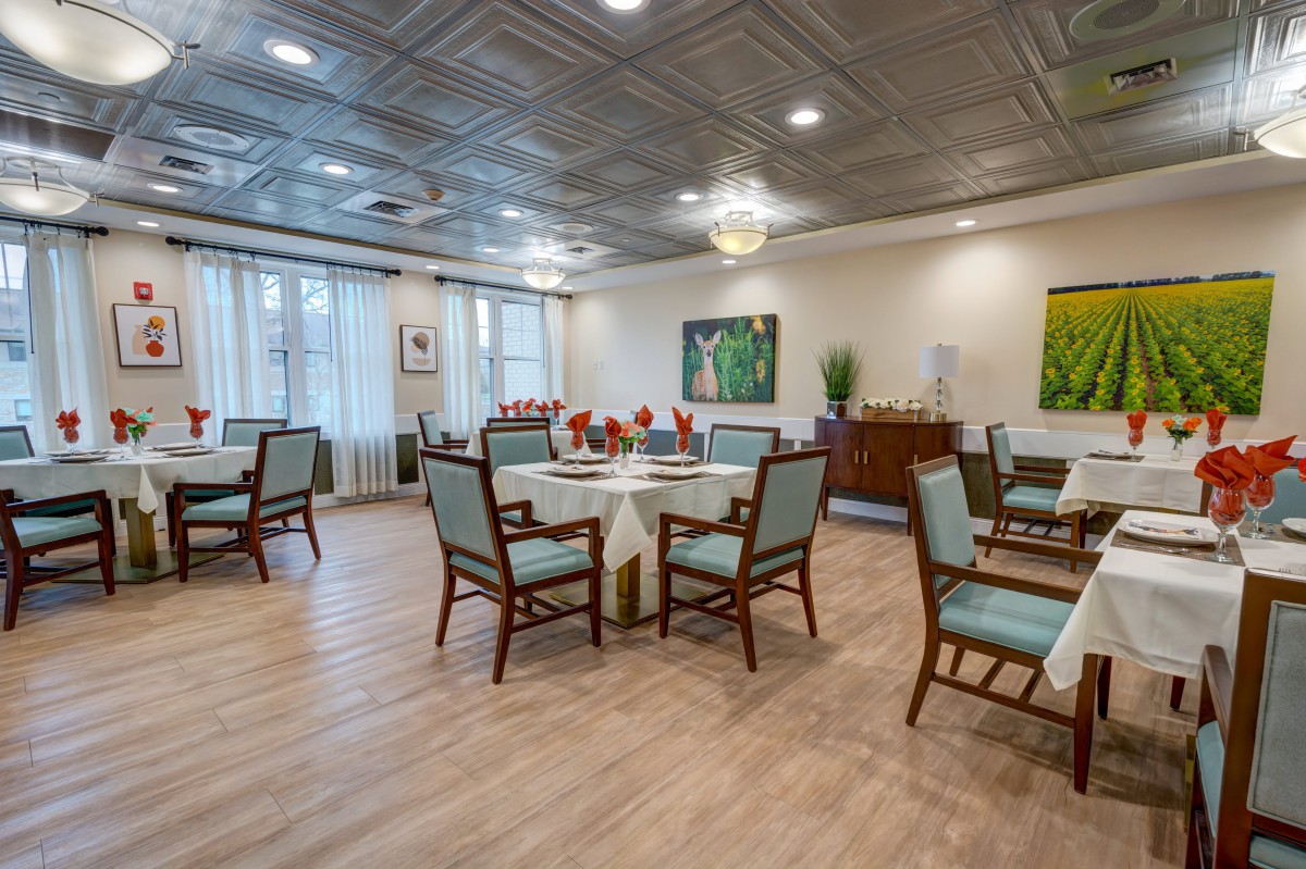 A well-decorated dining room with neatly arranged tables and chairs, complemented by elegant art pieces and ambient lighting.