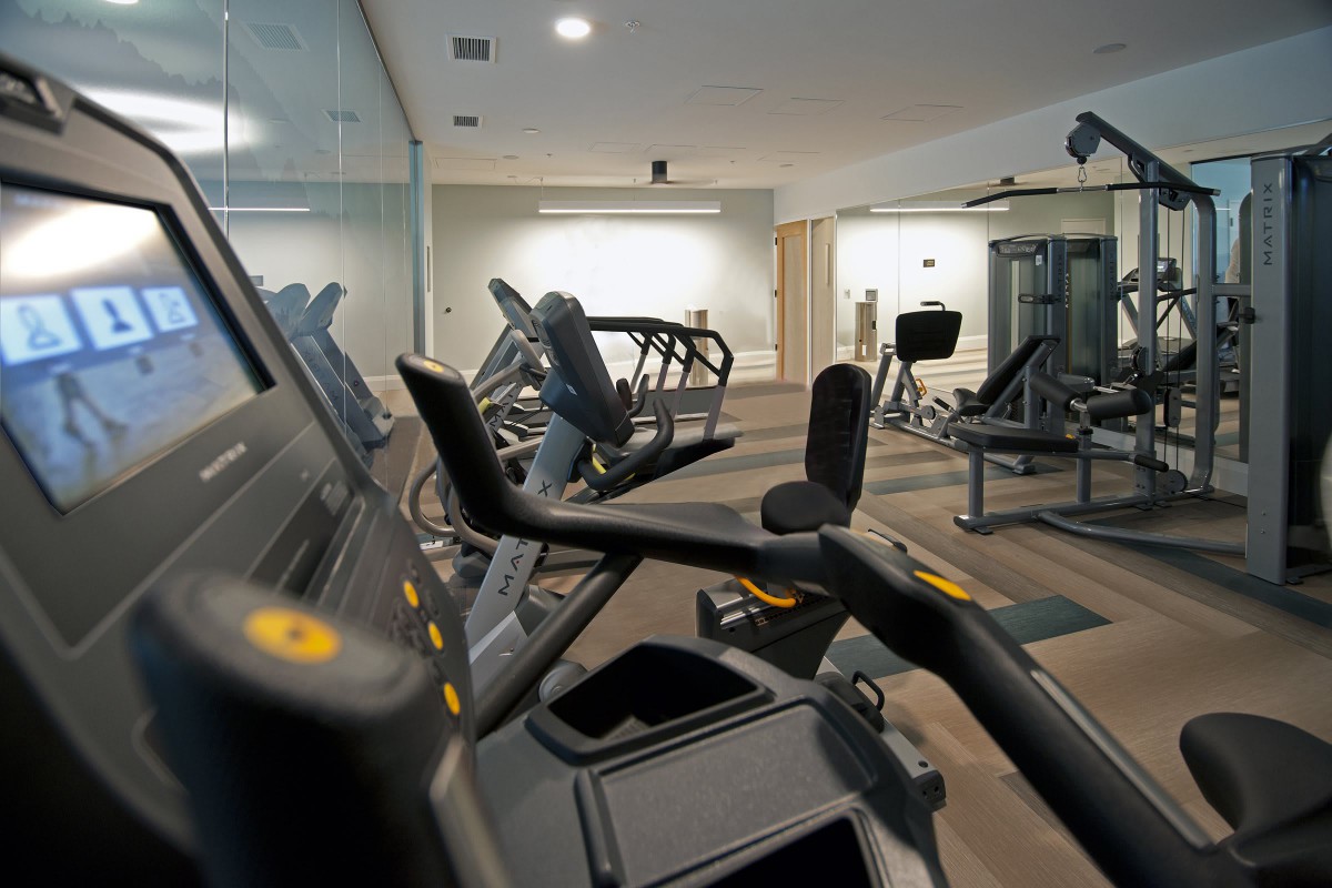 A modern gym with various exercise equipment including treadmills and machines.