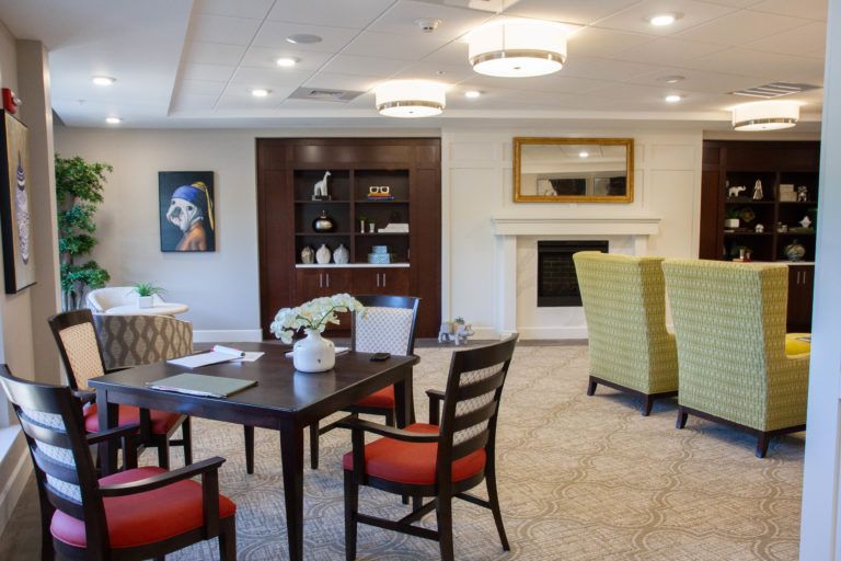 A cozy living room with modern furniture, featuring a table and chairs, a fireplace, and artwork on the wall.
