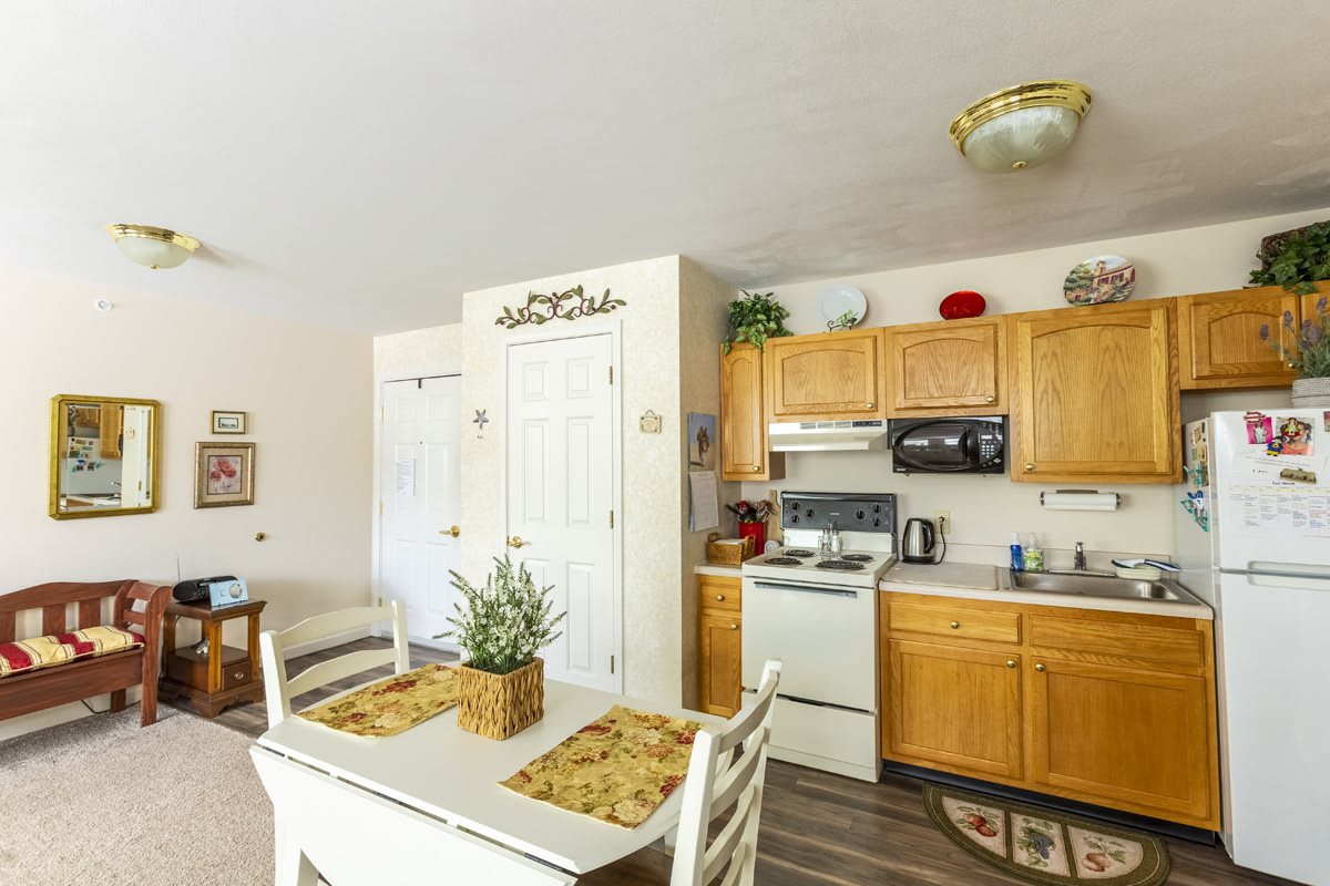 A cozy kitchen and dining area with wooden cabinets, a white stove, and a small table set for two.