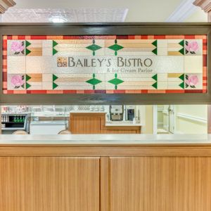 A brightly colored sign for Balee's Bistro above a wooden counter in an indoor setting.