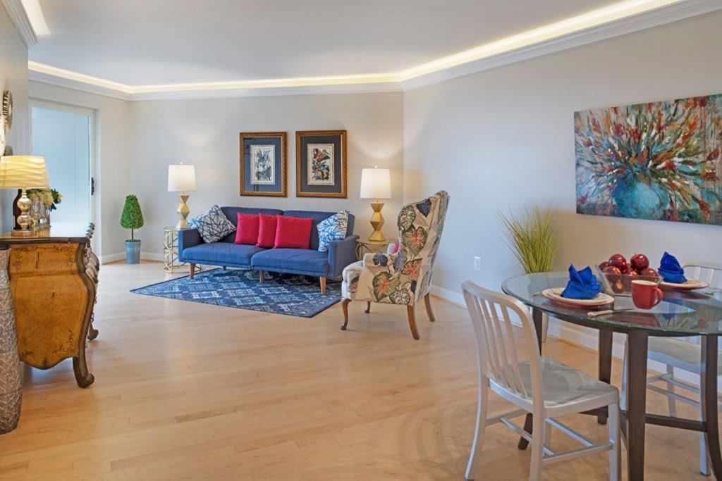 A spacious living room with modern furniture and decor, featuring a blue sofa, patterned chairs, and elegant lighting.