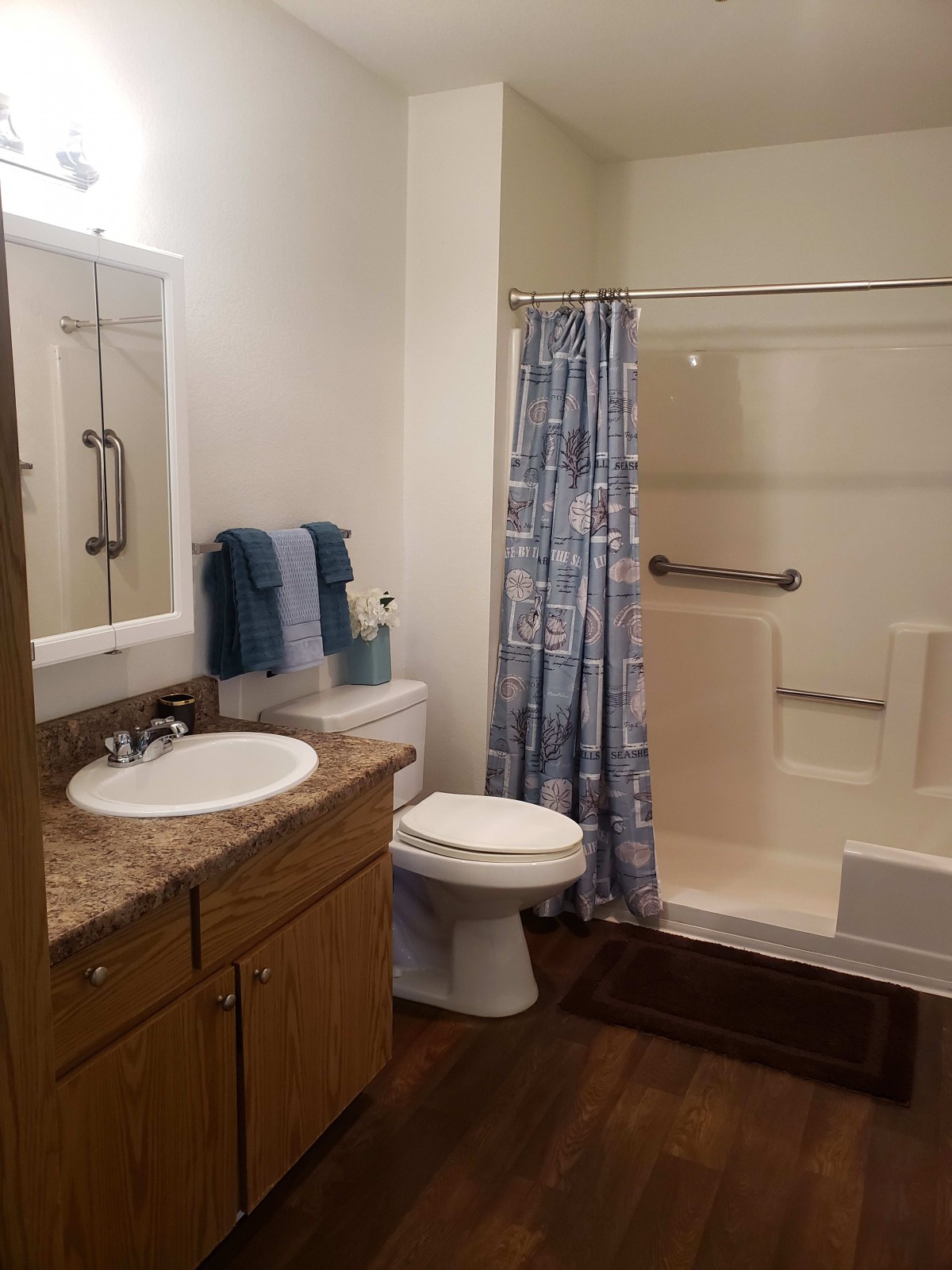 A clean and organized bathroom with a shower, toilet, sink, and storage cabinet.