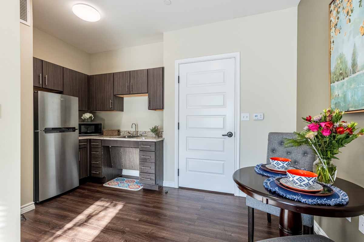 A modern apartment kitchen with stainless steel appliances and a neatly set dining table.