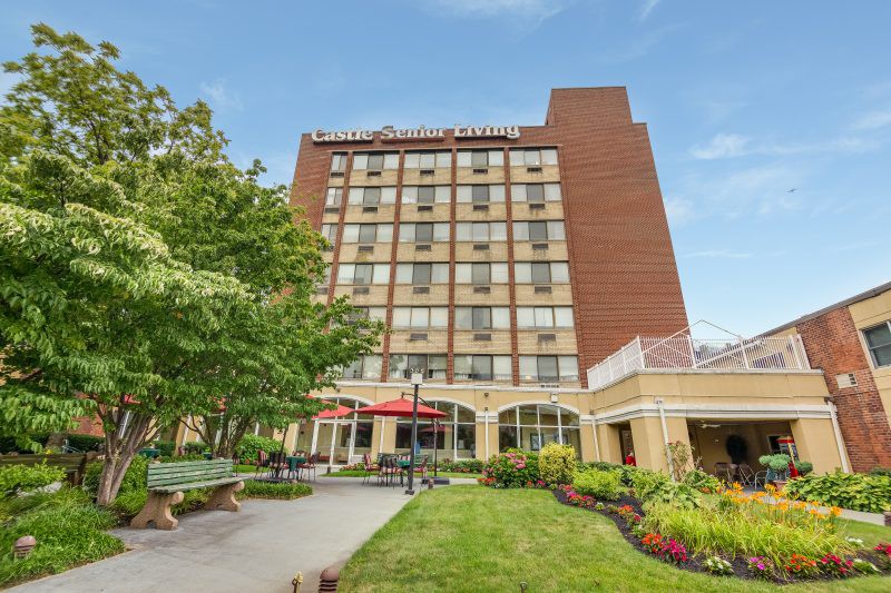 A view of a hotel building surrounded by greenery and a pathway.