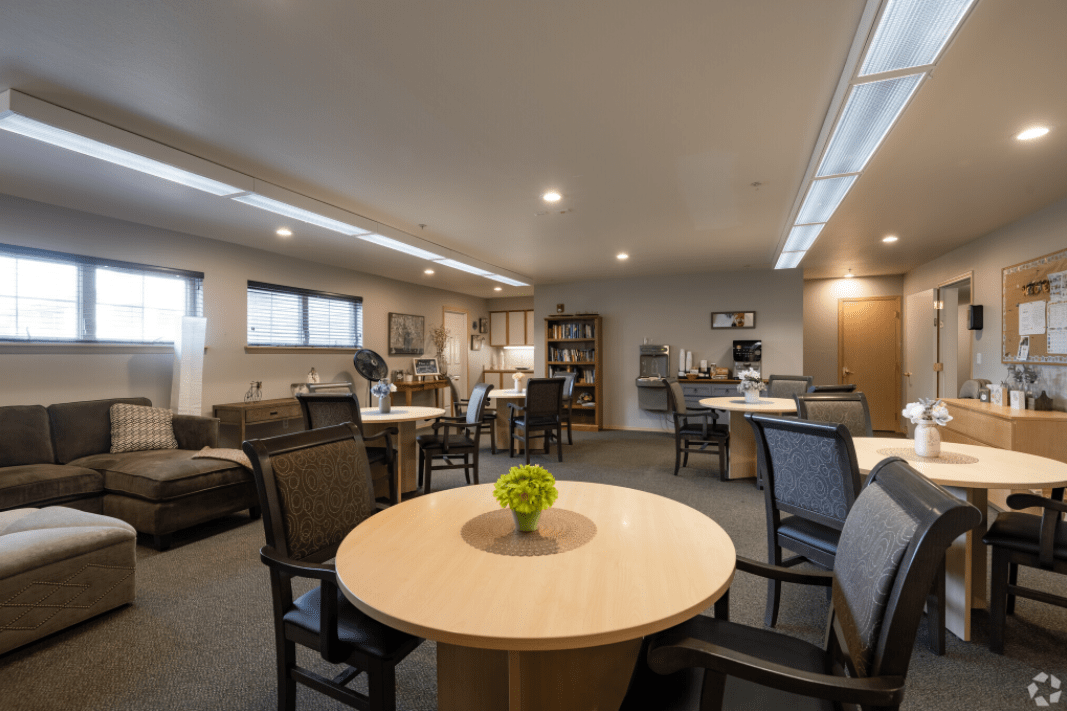 A spacious and well-lit office meeting room with round tables and comfortable chairs.