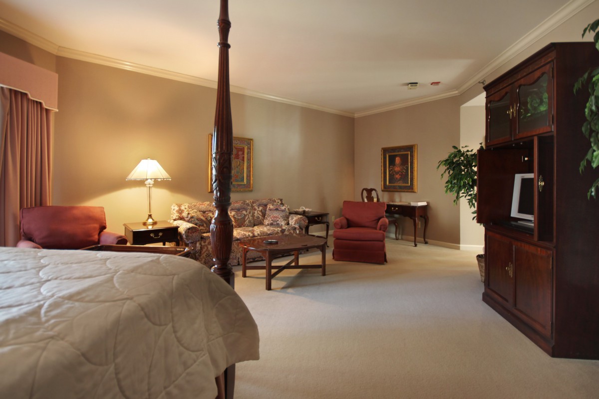 A cozy traditional bedroom with a seating area and warm lighting.