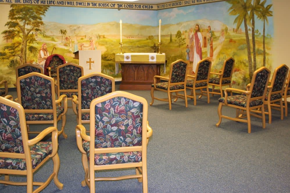 A small chapel with a mural, featuring an altar and arranged chairs.