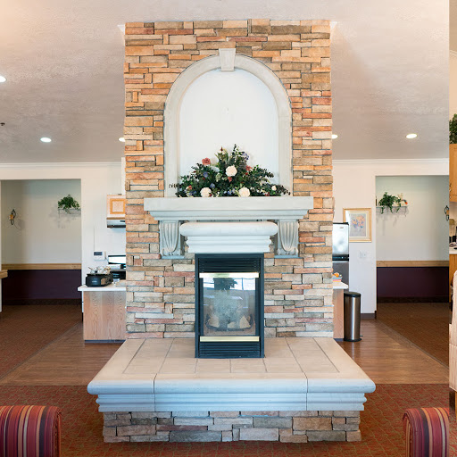 A cozy lobby featuring a decorative stone fireplace, enhanced with greenery.