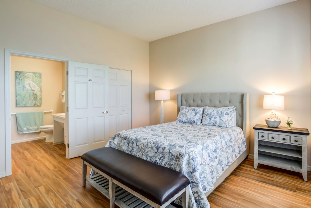 A well-furnished bedroom with a comfortable bed, two bedside lamps, and wooden flooring.