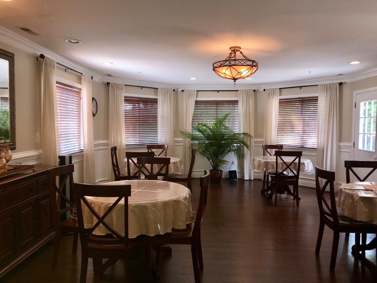 A cozy dining area with several tables, chairs, and a decorative chandelier.