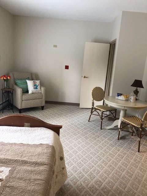 A cozy bedroom with a chair, table, and lamp.
