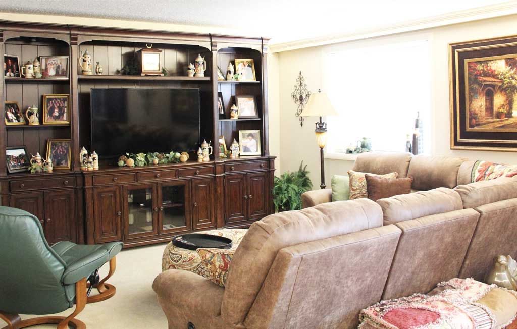 A cozy living room featuring a large entertainment center with a television, comfortable sofas, and decorative elements.