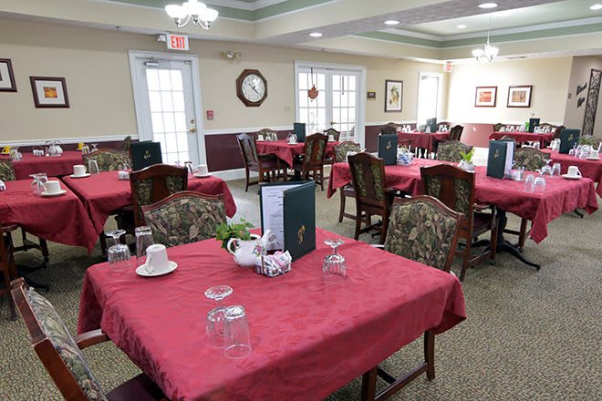 An elegant dining area with red tablecloths and neatly arranged tables and chairs.