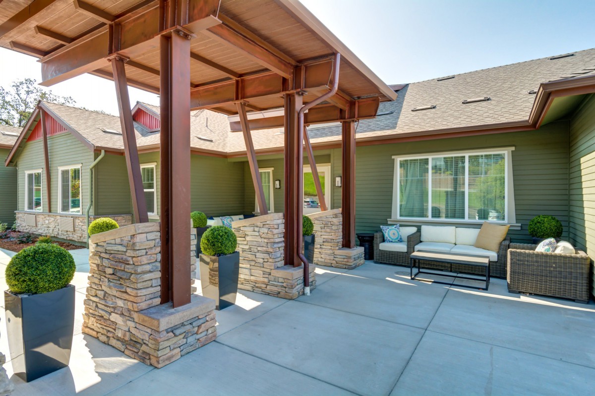 A modern patio area featuring stone columns and wooden beams, with comfortable outdoor seating.