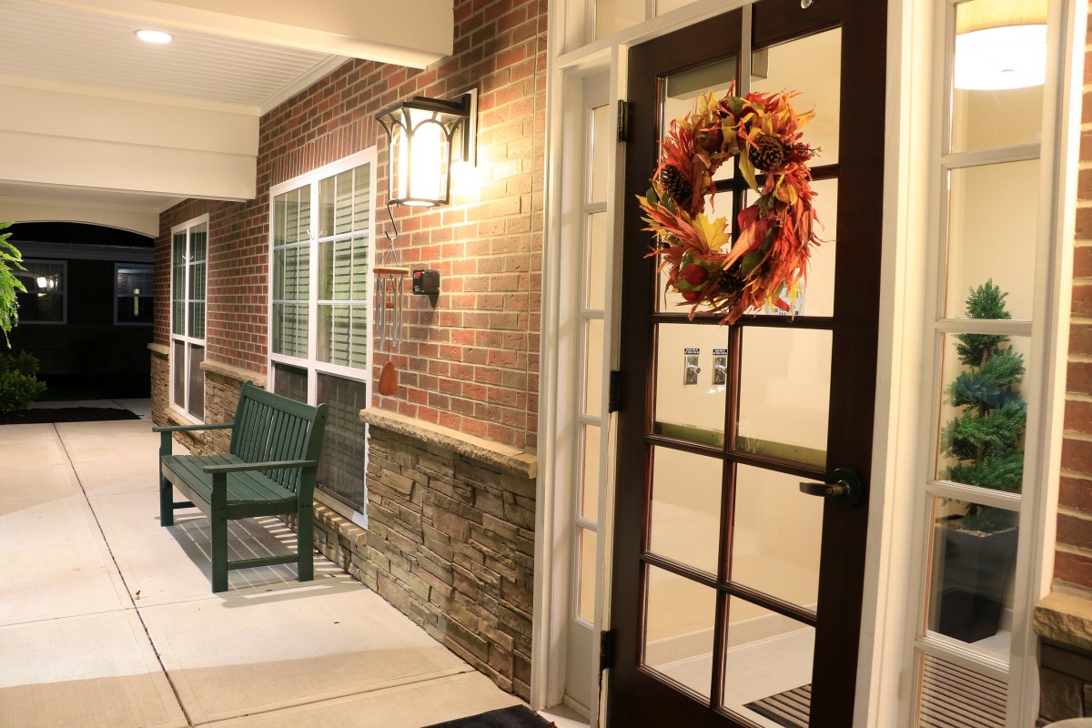 A cozy front porch decorated with an autumn wreath on the door.