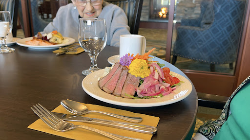 A beautifully arranged plate of sliced beef garnished with colorful flowers, set on a dining table.