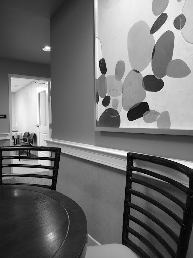 A minimalist interior scene featuring a table and chairs, complemented by abstract wall art.