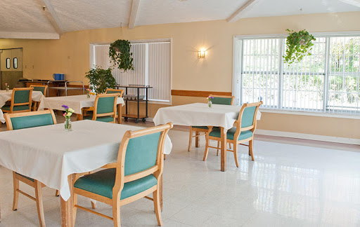 A spacious and inviting dining area featuring well-arranged tables and chairs, complemented by lush greenery.