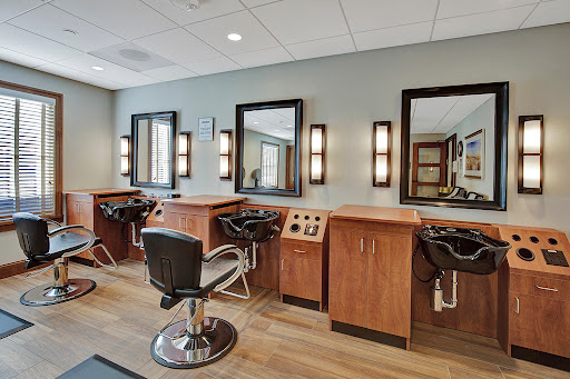 A modern hair salon featuring stylish chairs and well-lit mirrors.