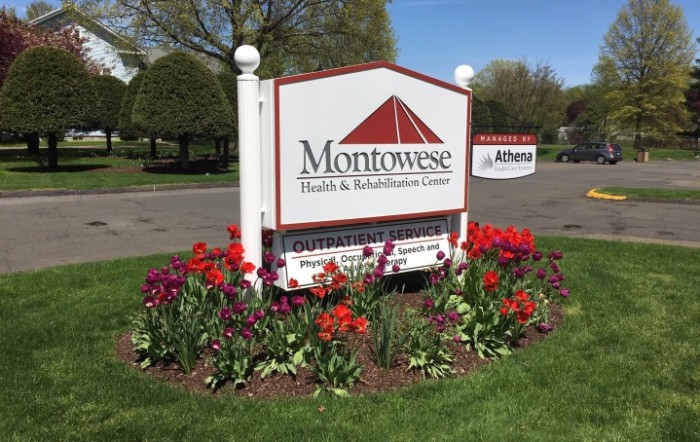 Montowese Health & Rehabilitation Center sign surrounded by blooming flowers.