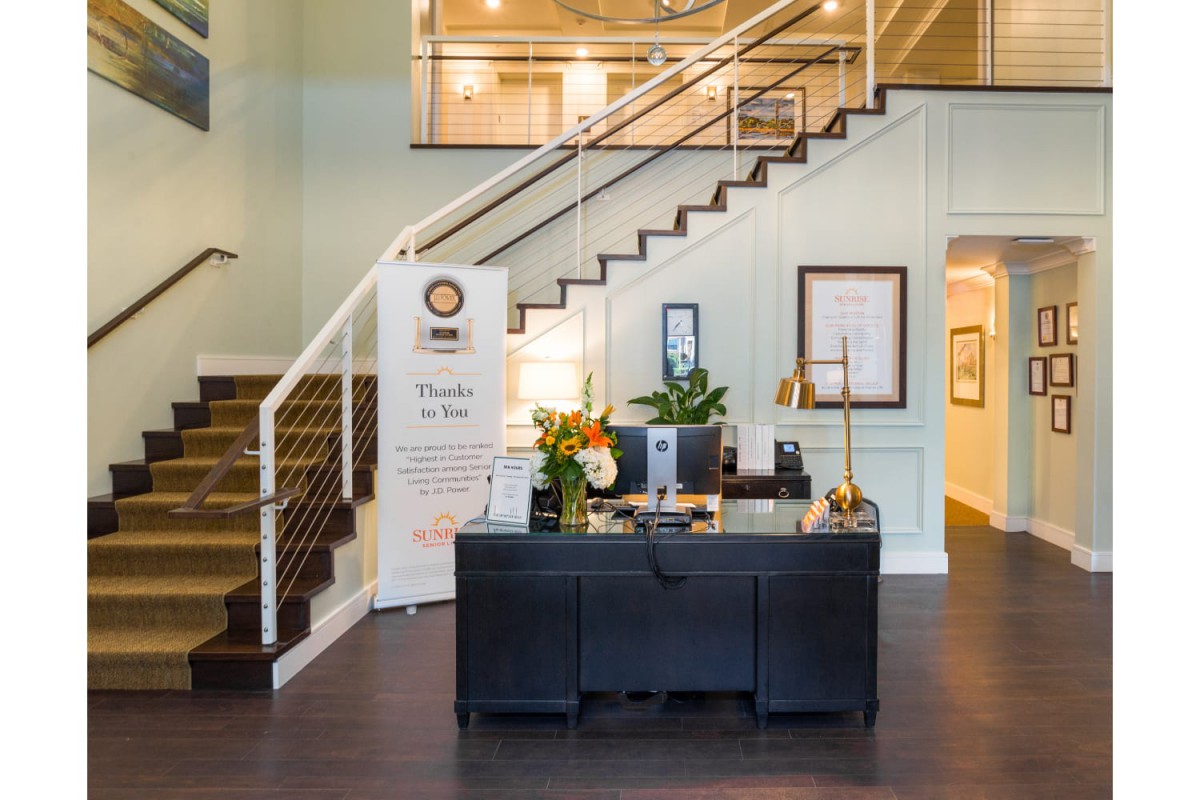 A welcoming reception area with a desk, computer, and floral arrangement, situated beside a staircase.