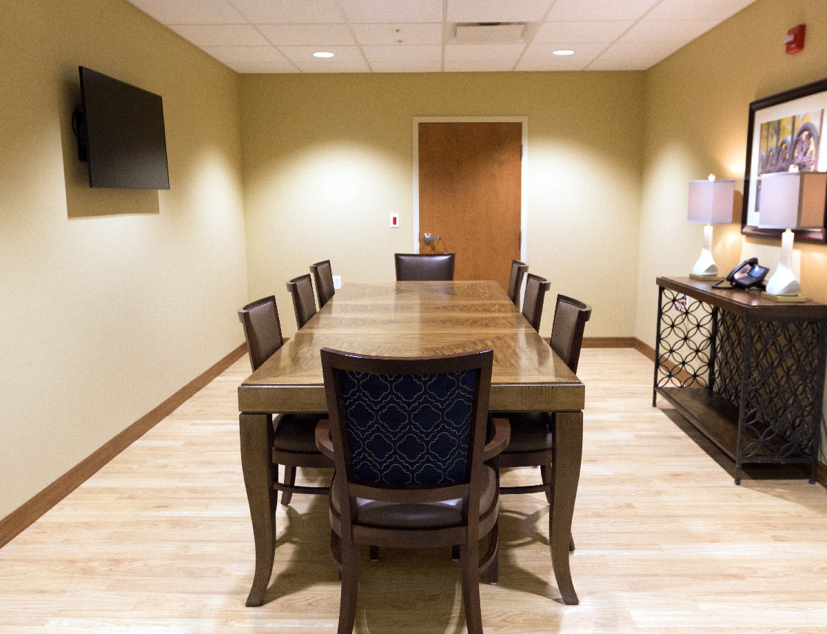 A well-appointed conference room with a large table and chairs, featuring modern decor and a wall-mounted television.
