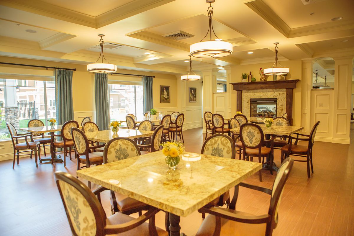 An elegant dining room featuring classic decor, chandeliers, and a cozy fireplace.
