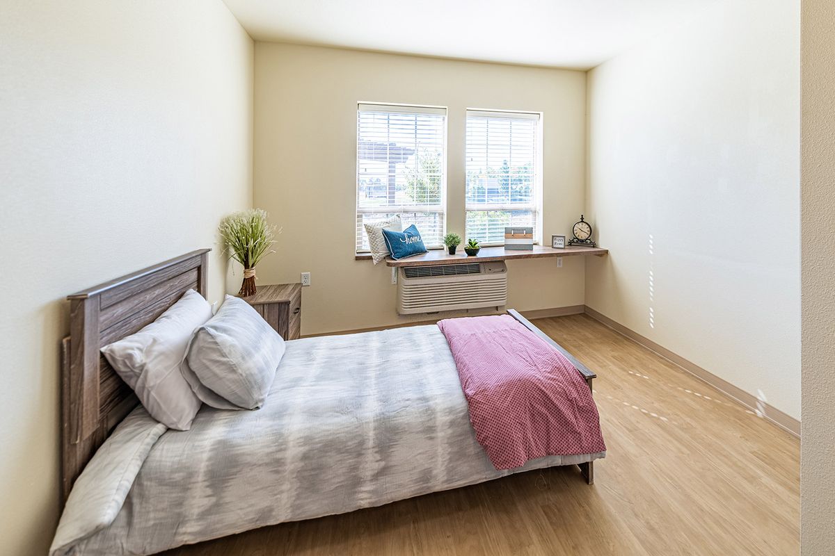 A bright and minimalist bedroom with a bed and large windows.