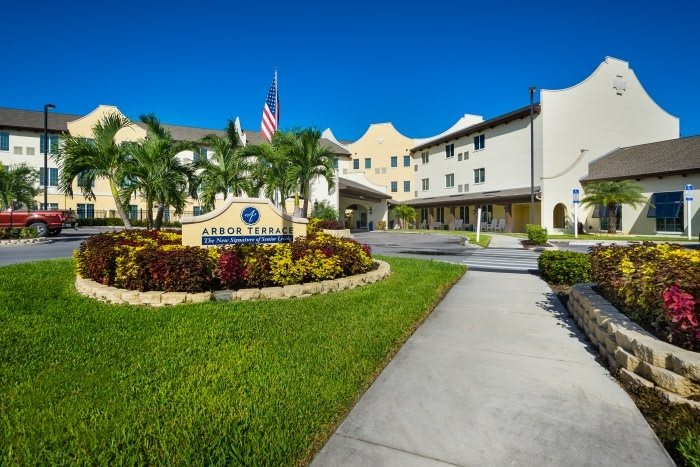 A hotel building with well-maintained landscaping and palm trees under a clear blue sky.