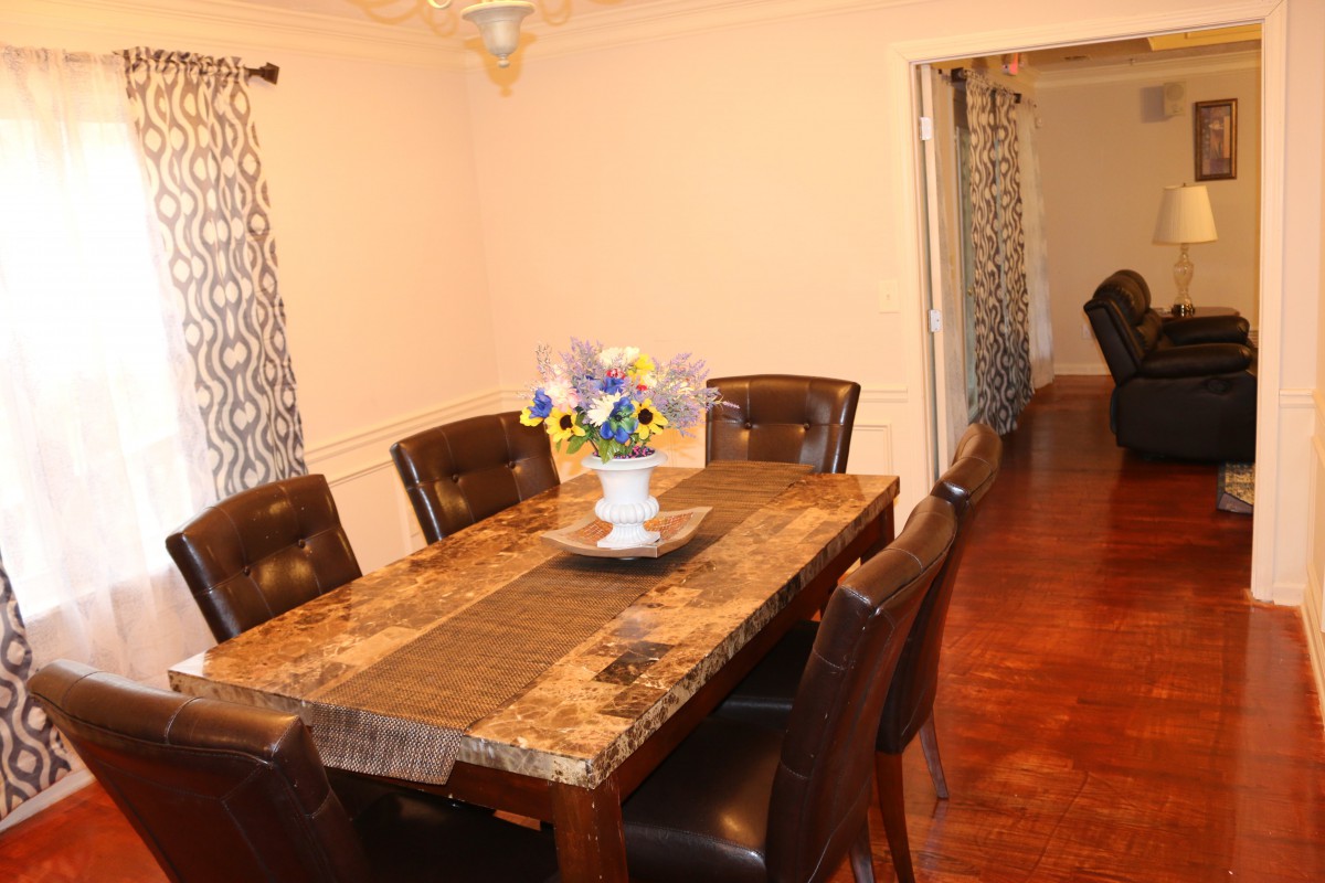 A cozy dining room with a wooden table, leather chairs, and a floral centerpiece.