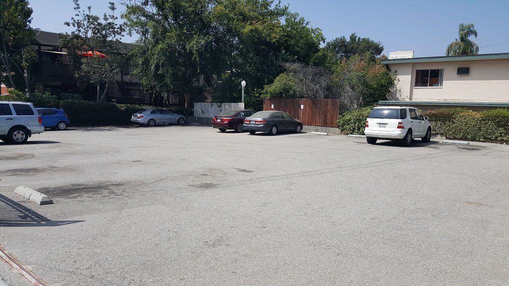 A quiet parking lot with several parked cars under a clear blue sky.
