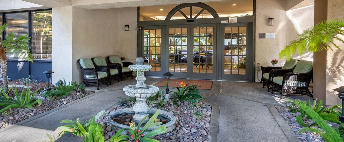 A welcoming entrance with a decorative fountain and greenery.
