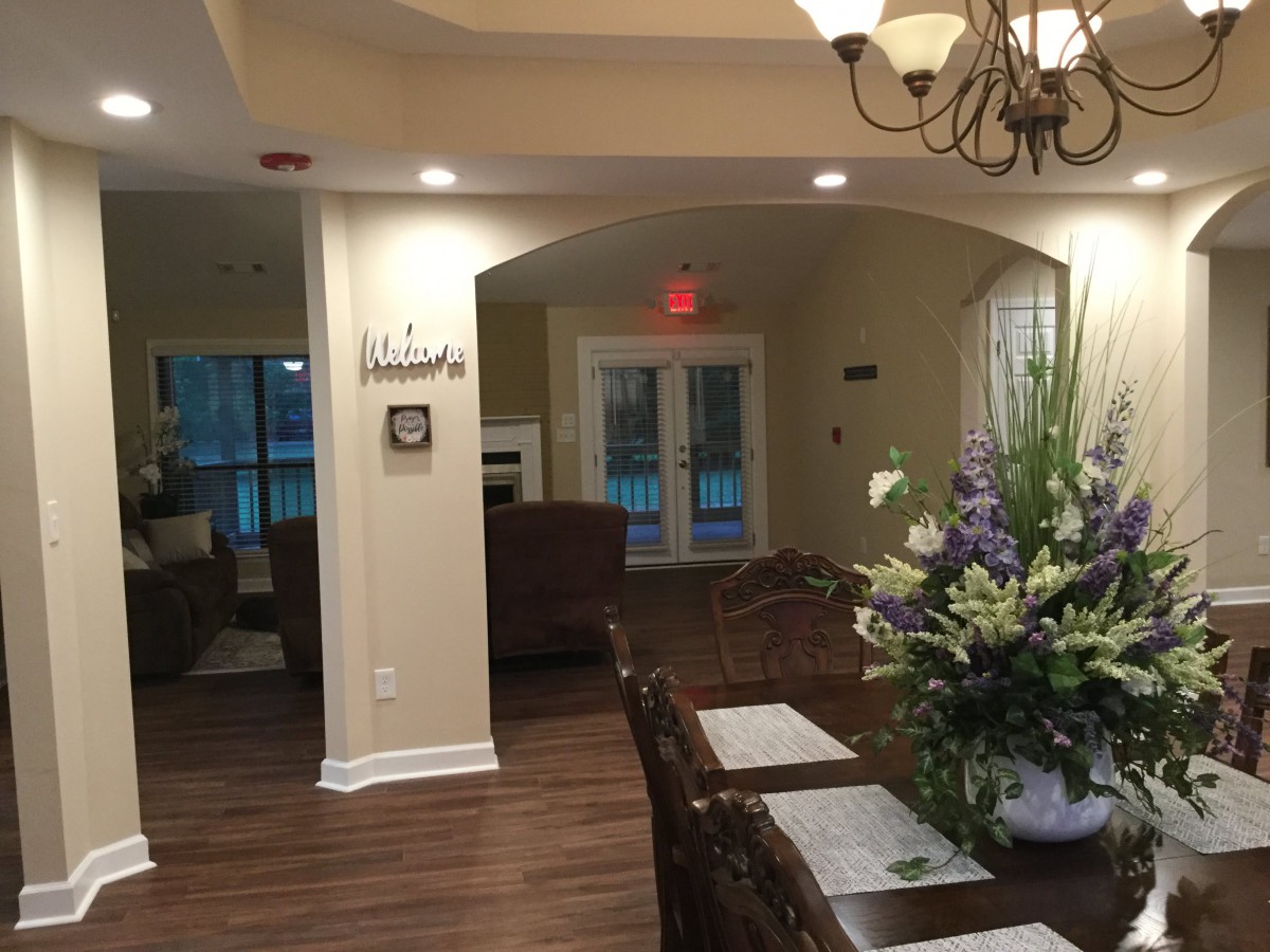 A cozy dining area with elegant decor, featuring a chandelier and floral centerpiece on a wooden table.