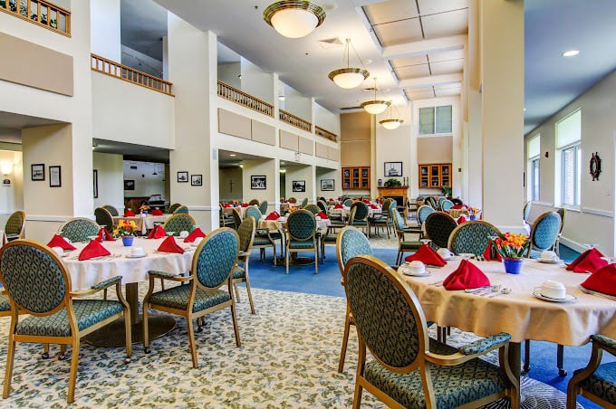 An elegant dining room with neatly arranged tables and chairs, featuring stylish lighting and place settings.