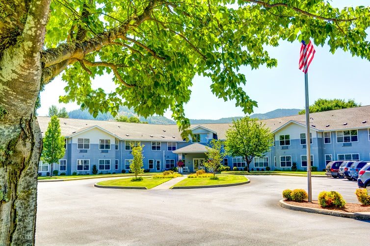 A bright, sunny day at a residential building surrounded by trees and an American flag.