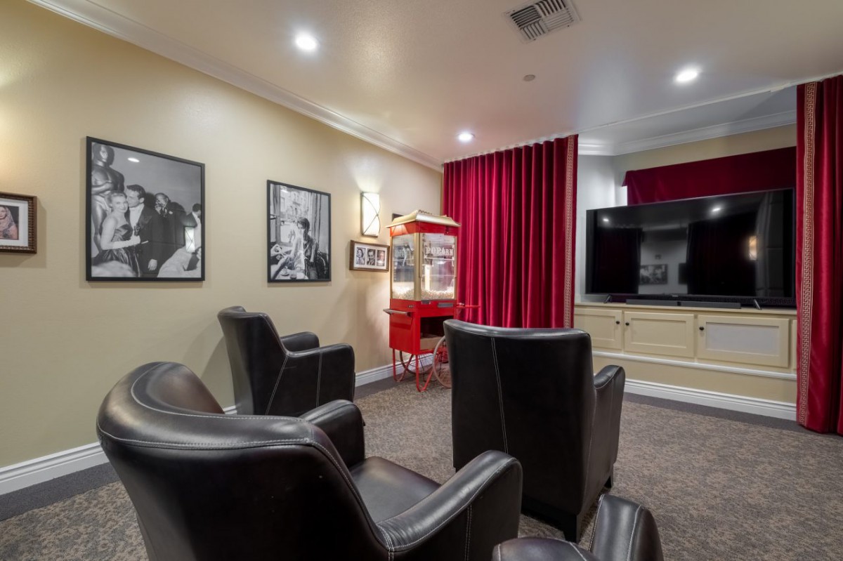 A comfortable home theater setup with leather seating, a large screen, and a popcorn machine.
