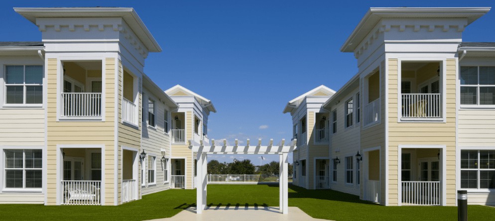 A view of a courtyard between two residential buildings on a clear day.