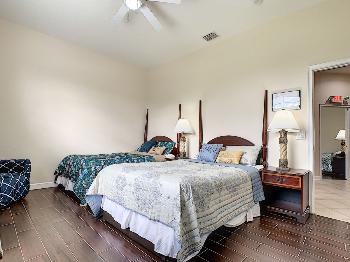 A cozy bedroom with twin beds, wooden floors, and a ceiling fan.