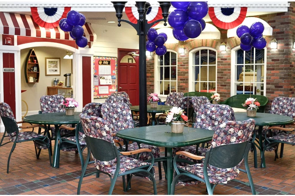 A festive indoor seating area with tables and chairs, adorned with balloons and patriotic decorations.