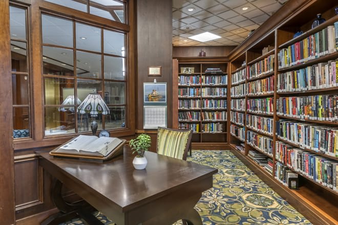 A cozy library corner with a reading table, surrounded by bookshelves.