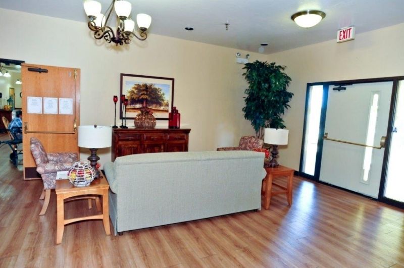 A cozy living room with a sofa, tables, lamps, and a painting on the wall.