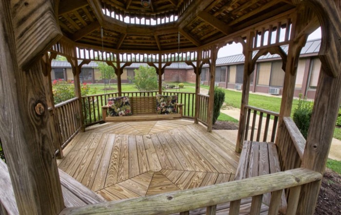 A wooden gazebo set in a garden courtyard, offering a peaceful outdoor retreat.
