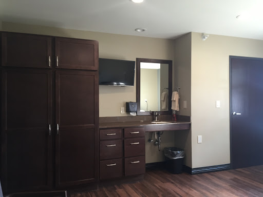 A modern interior featuring a wooden vanity with a mirror, storage cabinets, and a wall-mounted TV.