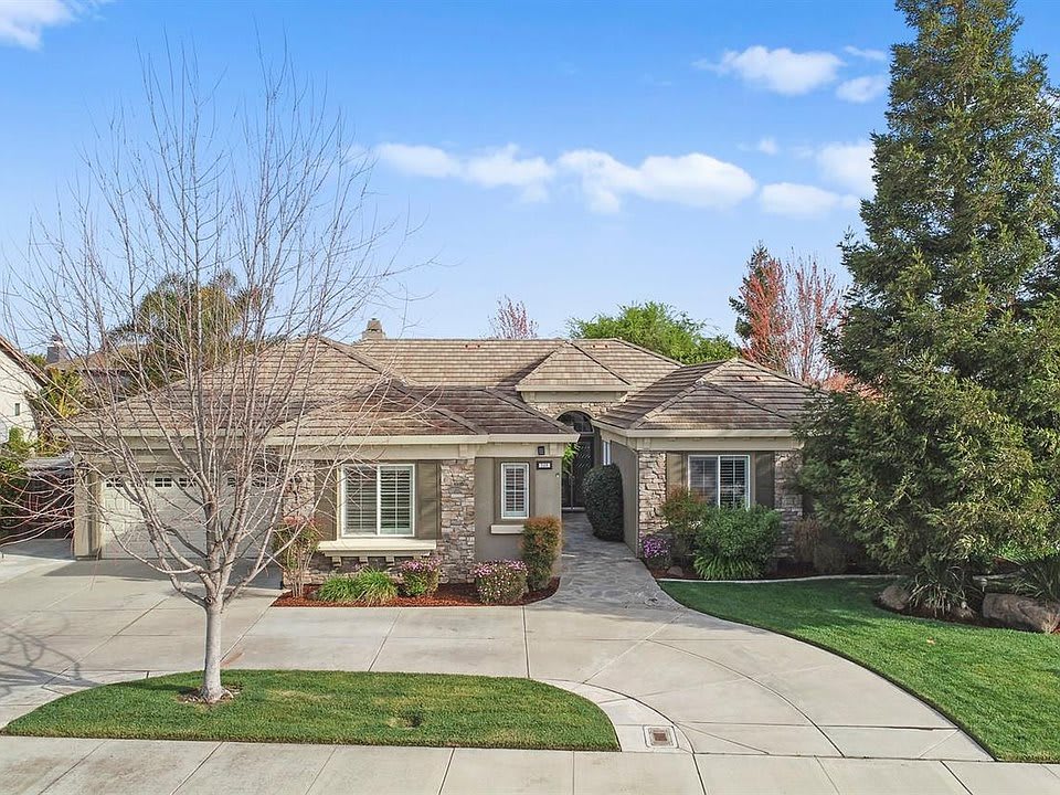 A suburban single-story house with a spacious driveway and landscaped front yard.